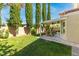 Backyard featuring a covered patio with a table and chairs, surrounded by tall, slender trees at 2708 Norbeck St, Las Vegas, NV 89117