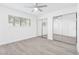 Bedroom features sleek sliding mirror closet doors, ceiling fan, and light gray wood-look flooring at 3805 San Angelo Ave, Las Vegas, NV 89102