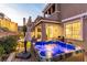 Well-lit backyard featuring a hot tub, covered patio, and landscaped surroundings at 39 Castleton Tower Ct, Henderson, NV 89011