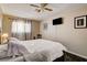 This bedroom features a ceiling fan, mounted TV, and curtains for privacy at 3912 Palos Verdes St, Las Vegas, NV 89119