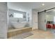 Bright bathroom features a modern, free-standing tub, travertine floors, and a stylish sliding barn door at 6419 Eldora Ave, Las Vegas, NV 89146