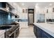 Gourmet kitchen boasts stainless appliances, white cabinets, blue backsplash, and center island with white countertop at 764 Ricota Ct, Henderson, NV 89012