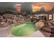 Lush backyard with a freeform pool, waterfall feature, rock accents, and covered patio area at 764 Ricota Ct, Henderson, NV 89012