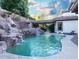 Inviting backyard swimming pool featuring a rock waterfall feature, seating area, and lush landscaping at 764 Ricota Ct, Henderson, NV 89012