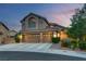 Beautifully lit two-story house showcasing a three-car garage, tile roof, and landscaped front yard at twilight at 8253 Ruby Mountain Way, Las Vegas, NV 89128