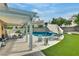 Backyard oasis featuring a covered patio, outdoor seating, and a sparkling in-ground pool and turf at 8253 Ruby Mountain Way, Las Vegas, NV 89128