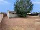 View of the backyard of a single-story house with a large shade tree, fence line, and ample open space at 1004 Stone River Dr, North Las Vegas, NV 89030