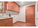 Well-lit laundry room with wood floors, stainless steel sink, wood cabinets, and washer hookups at 1008 Trophy Hills Dr, Las Vegas, NV 89134