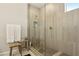 Modern bathroom featuring a walk-in shower with sleek tile and glass enclosure and wooden stool with neatly folded white towels at 10196 Sequoia Glen Ave, Las Vegas, NV 89166