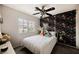 This bedroom features a decorative accent wall, ceiling fan, and a window with neighborhood views at 10400 Beautiful Fruit St, Las Vegas, NV 89183