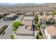 Wide aerial view showcasing a desert community filled with earth-toned homes and mature landscaping at 10565 Olinda St, Las Vegas, NV 89179