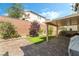 Serene backyard featuring a covered patio, brick pavers, artificial grass, and lush landscaping creating a tranquil outdoor space at 10565 Olinda St, Las Vegas, NV 89179
