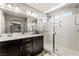 Bright bathroom features a glass-enclosed shower, double sinks and a modern vanity with dark brown cabinets at 10565 Olinda St, Las Vegas, NV 89179