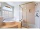 Bright bathroom featuring a soaking tub with glass block window and a glass enclosed shower with gold trim at 11237 Campsie Fells Ct, Las Vegas, NV 89141