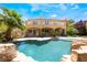 Stunning backyard with a pool, rock features, mature palm trees, and a covered patio, perfect for entertaining at 11237 Campsie Fells Ct, Las Vegas, NV 89141