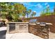 A stunning outdoor kitchen featuring a built-in BBQ, mini fridge, and stone accents at 11237 Campsie Fells Ct, Las Vegas, NV 89141