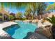 Backyard pool and spa with rock waterfall features surrounded by lush, mature landscaping and palm trees at 11237 Campsie Fells Ct, Las Vegas, NV 89141