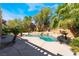 A tropical swimming pool with surrounding mature trees and lush landscaping at 11237 Campsie Fells Ct, Las Vegas, NV 89141