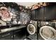 A stylish laundry room with black cabinets, floral wallpaper, and modern washer and dryer units at 11578 Suburban Rd, Las Vegas, NV 89135