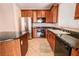 Kitchen with stainless steel refrigerator, black appliances, wood cabinetry, tile floors and granite countertops at 11900 Calle De Sol Dr, Las Vegas, NV 89138