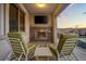 Cozy covered patio with stone fireplace, TV, and comfortable lounge chairs overlooking the pool at 12219 Crystal Shore Ave, Las Vegas, NV 89138