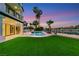 A backyard view of the in-ground pool, outdoor living space, manicured lawn, and lake at 2589 Sun Reef Rd, Las Vegas, NV 89128