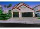 Exterior view of a home featuring a two-car garage with dark brown doors and well manicured landscaping at 2589 Sun Reef Rd, Las Vegas, NV 89128
