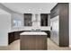 Well-lit kitchen featuring dark wood cabinets, a stainless steel refrigerator, and a white countertop island at 2589 Sun Reef Rd, Las Vegas, NV 89128
