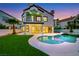 Backyard view of a pool and spa with a two-story home in the background, enhanced by artificial turf at 2589 Sun Reef Rd, Las Vegas, NV 89128