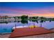 A scenic view of a lake with a private dock, boat, and paddle boats, reflecting serene water at 2589 Sun Reef Rd, Las Vegas, NV 89128