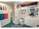 Garage bathroom with blue carpet, white fixtures, and colorful decor at 2650 Sagebrush Ave, Pahrump, NV 89048