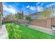 Expansive backyard with artificial turf, brick perimeter, a seating area, and manicured landscaping at 3144 Tronzano Ave, Henderson, NV 89044