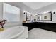 Luxury bathroom featuring dual vanities with black cabinetry, soaking tub, and elegant tile flooring at 3144 Tronzano Ave, Henderson, NV 89044
