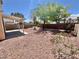 Private backyard featuring a covered patio, gravel landscape, mature trees, and blooming shrubbery at 3919 Lilac Haze St, Las Vegas, NV 89147