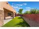 Relaxing backyard features a covered patio, lush artificial turf, a stone pillar accent, and a brick wall at 5384 Candlespice Way, Las Vegas, NV 89135