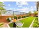 Landscaped backyard features artificial grass, green shrubs, and a sleek black fence, perfect for outdoor enjoyment at 5530 Hill Spire St, Las Vegas, NV 89166