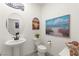 Stylish powder room with pedestal sink, ocean-themed decor, and decorative wall art at 5530 Hill Spire St, Las Vegas, NV 89166