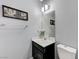 Half bathroom featuring a vanity with white sink, framed mirror, and patterned gray wallpaper at 6276 Point Isabel Way, Las Vegas, NV 89122
