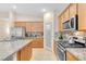Well-lit kitchen with stainless steel appliances, granite countertops, a pantry door, and maple cabinets at 7070 Cinder Horse St, Las Vegas, NV 89131