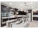 Modern kitchen featuring dark cabinetry, stainless steel appliances, and a waterfall edge island with marble-patterned countertop at 724 Step Beach St, Las Vegas, NV 89138