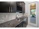 Butler's pantry with granite countertop, stainless steel sink, and black cabinets lead to backyard at 724 Step Beach St, Las Vegas, NV 89138