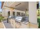 Outdoor kitchen with stainless steel BBQ and bar with view of backyard putting green at 724 Step Beach St, Las Vegas, NV 89138