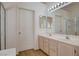 Bright bathroom featuring a double sink vanity, large mirror with vanity lighting and glass enclosed shower at 7927 W Oquendo Rd, Las Vegas, NV 89113