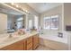 Bathroom features a double sink vanity, large mirror and a soaking tub next to a window at 8136 Shady Glen Ave, Las Vegas, NV 89131