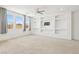 Large living room with built-in shelving, neutral carpet, and natural light from multiple windows at 8724 Scalpay St, Las Vegas, NV 89166