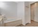 Bright bathroom showcasing a soaking tub with white cabinets and wood-look flooring at 9215 Penn Station St, Las Vegas, NV 89123