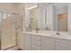 Bright bathroom featuring double sinks, a glass-enclosed shower, and modern lighting at 9215 Penn Station St, Las Vegas, NV 89123
