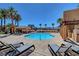 Community pool deck with lounge seating and covered patio area surrounded by lush tropical landscaping at 9215 Penn Station St, Las Vegas, NV 89123