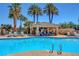 Community pool with lounge seating and covered patio area surrounded by lush tropical landscaping at 9215 Penn Station St, Las Vegas, NV 89123