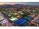 Aerial view of lit community tennis courts and pools with the city skyline in the distance at 9409 January Dr, Las Vegas, NV 89134
